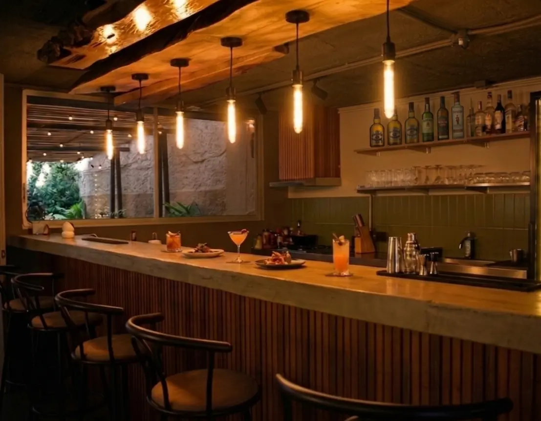 Barra de Casa Apolonia iluminada con luces cálidas, cocteles y aperitivos